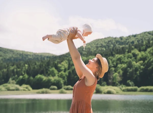 Mother and baby. Concept of natural maternity and motherhood. Beautiful woman and little baby happy together in green nature background. Loving mom with child outdoors.