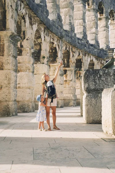 Tourist woman with small kids in Roman Amphitheater Arena like as Coliseum - famous travel destination in Pula, Croatia. Happy mother and children on vacation in Europe. Family Active Travel.