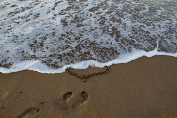 Kalp Kumda Çizilmiş Sahilde Ayak Izleri Önünde Deniz Köpüğü Var — Stok fotoğraf