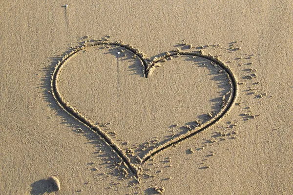 Kalp arka planda bir kumsalın kumunu çiziyor. Romantik alan.