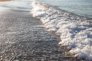 Deniz dalgaları ve kumla kaplı güzel bir deniz manzarası. Kumsalda deniz dalgaları.