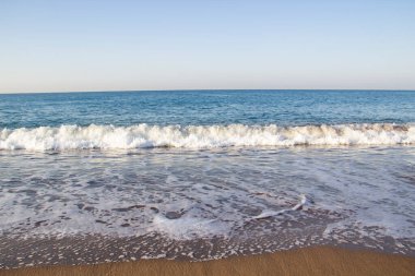 Deniz dalgaları ve kumla kaplı güzel bir deniz manzarası. Kumsalda deniz dalgaları.