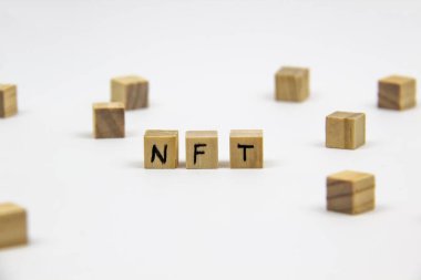 Beyaz arkaplandaki tahta küplere NFT (ödenebilir olmayan jeton) yazıldı. Finansal olmayan jetonlar konsepti NFT.