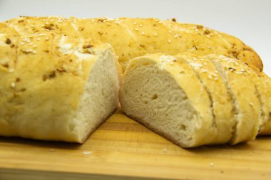 Evde un ile pişirilmiş buğday ekmeği. Ahşap tahta üzerinde arka planda dilimlenmiş ekmek. GDO 'suz yemek. Baharatlı ev yapımı ekmek..