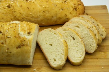 Evde un ile pişirilmiş buğday ekmeği. Ahşap tahta üzerinde arka planda dilimlenmiş ekmek. GDO 'suz yemek. Baharatlı ev yapımı ekmek..