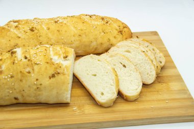 Evde un ile pişirilmiş buğday ekmeği. Ahşap tahta üzerinde arka planda dilimlenmiş ekmek. GDO 'suz yemek. Baharatlı ev yapımı ekmek..