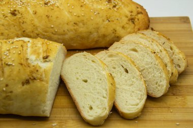 Evde un ile pişirilmiş buğday ekmeği. Ahşap tahta üzerinde arka planda dilimlenmiş ekmek. GDO 'suz yemek. Baharatlı ev yapımı ekmek..