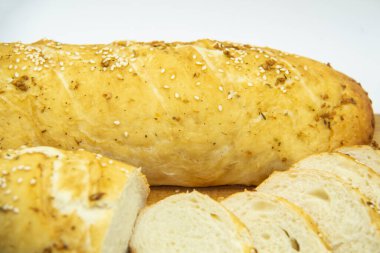 Evde un ile pişirilmiş buğday ekmeği. Ahşap tahta üzerinde arka planda dilimlenmiş ekmek. GDO 'suz yemek. Baharatlı ev yapımı ekmek..