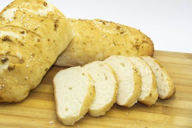 Evde un ile pişirilmiş buğday ekmeği. Ahşap tahta üzerinde arka planda dilimlenmiş ekmek. GDO 'suz yemek. Baharatlı ev yapımı ekmek..