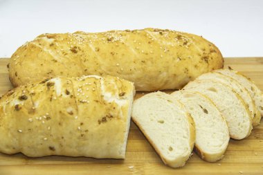 Evde un ile pişirilmiş buğday ekmeği. Ahşap tahta üzerinde arka planda dilimlenmiş ekmek. GDO 'suz yemek. Baharatlı ev yapımı ekmek..