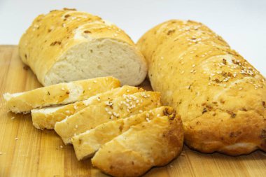 Evde un ile pişirilmiş buğday ekmeği. Ahşap tahta üzerinde arka planda dilimlenmiş ekmek. GDO 'suz yemek. Baharatlı ev yapımı ekmek..