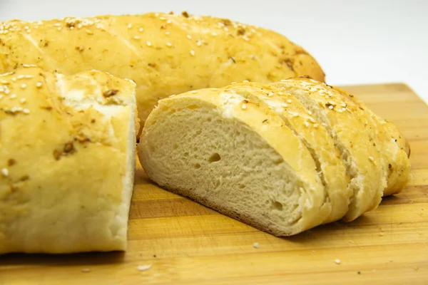 Evde un ile pişirilmiş buğday ekmeği. Ahşap tahta üzerinde arka planda dilimlenmiş ekmek. GDO 'suz yemek. Baharatlı ev yapımı ekmek..