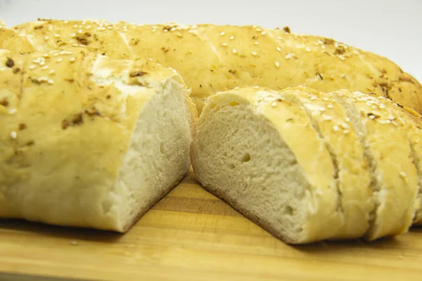 Evde un ile pişirilmiş buğday ekmeği. Ahşap tahta üzerinde arka planda dilimlenmiş ekmek. GDO 'suz yemek. Baharatlı ev yapımı ekmek..