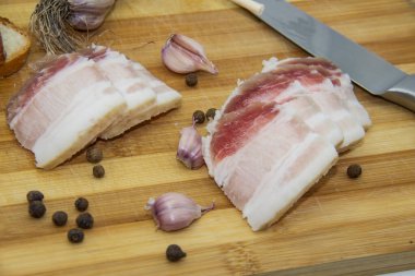 Ukrayna ürünleri çiğ domuz yağı, biber, sarımsak, bıçak, salo dilimleri ahşap kesim tahtasının üzerinde duruyor. Ukrayna geleneksel gıda konsepti.