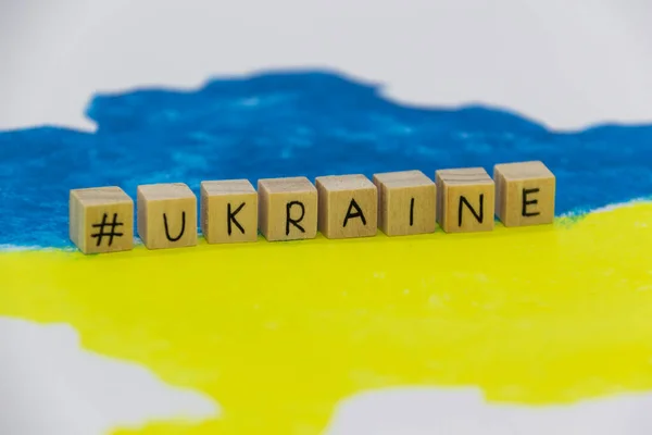 在乌克兰地图的背景上用蓝色和黄色标出的木制立方体上的乌克兰字 — 图库照片