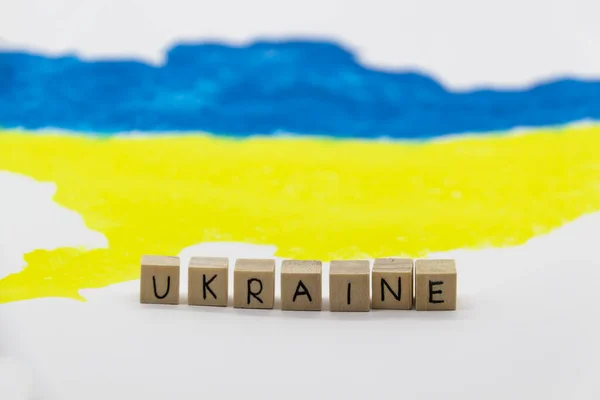 在乌克兰地图的背景上用蓝色和黄色标出的木制立方体上的乌克兰字 — 图库照片