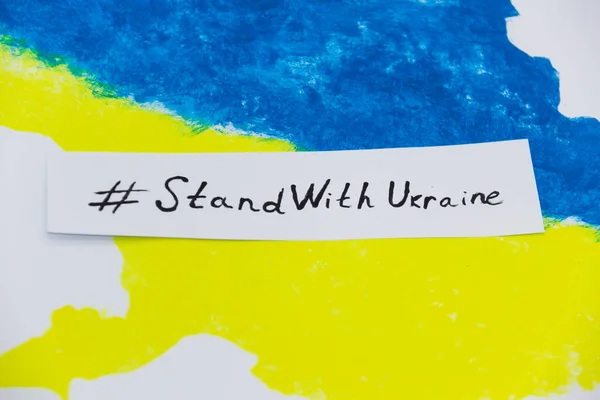 Üzerinde Ukrayna bayrağı bulunan mavi ve sarı renkli Ukrayna haritası UKRAINE ile dur.