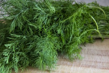 Kesme tahtasındaki bir demet dereotu. Vejetaryen baharatlı dereotu, masada bir sürü dereotlu sebze..