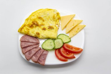 Lezzetli kahvaltı ya da omletli omlet sosis, domates, salatalık ve beyaz tabakta peynir parçaları..