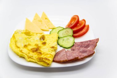 Lezzetli kahvaltı ya da omletli omlet sosis, domates, salatalık ve beyaz tabakta peynir parçaları..