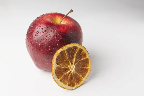 흰 배경에 빨간 사과와 마른 오렌지 한 조각 — 스톡 사진
