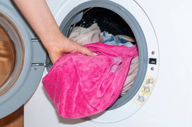 Bir kadının eli çamaşır makinesinden çamaşırları çıkarır.