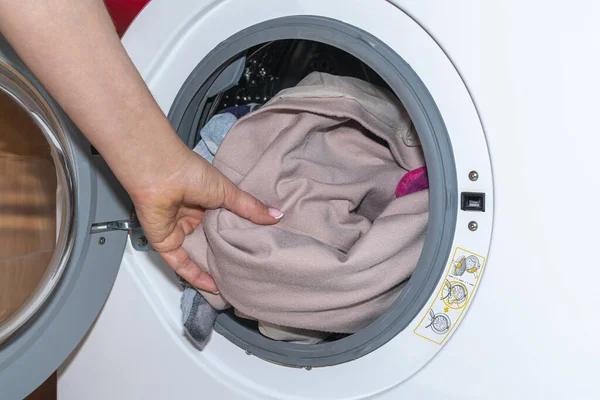 A womans hand takes the laundry out of the washing machine — Stock Photo, Image