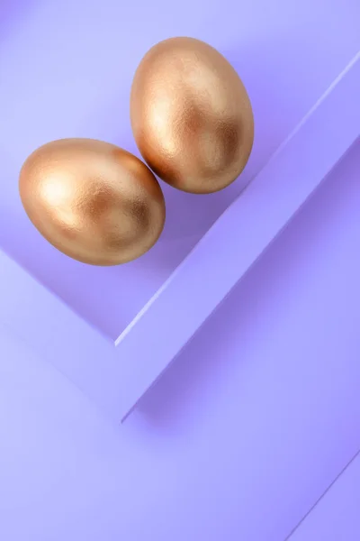 Elegante conceito de Páscoa de ovos dourados no moderno fundo roxo. Páscoa ovo de ouro flat lay. Feliz cartão de Páscoa. Espaço de cópia para texto. — Fotografia de Stock