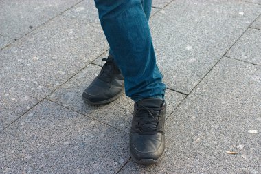Kot pantolon ve siyah spor ayakkabılarla bacak bacak bacak üstüne attım.
