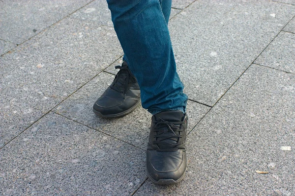 穿牛仔裤和黑色运动鞋的双腿交叉 — 图库照片