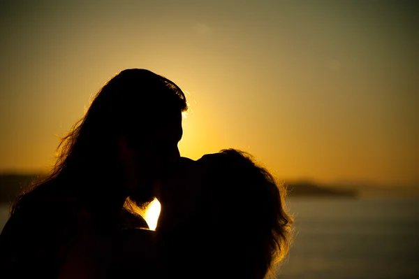 Milující pár líbání na pláži při západu slunce Stock Obrázky