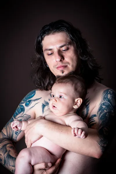 Jovem homem atraente segurando um bebê recém-nascido estúdio tiro Imagem De Stock