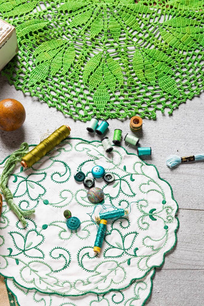 Set of sewing and embroidery supplies on a table: sewing thread, buttons, crochet, embroidered doiles, scissors