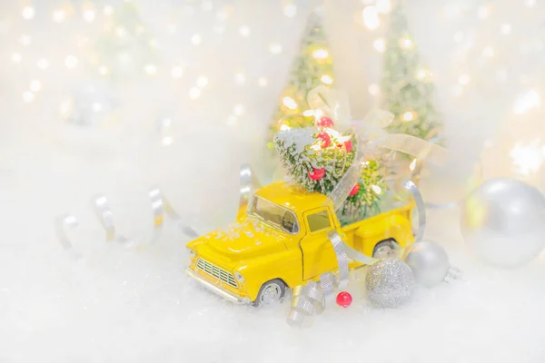 Sárga autó hordozó díszített karácsonyfa fehér havas háttér. — Stock Fotó