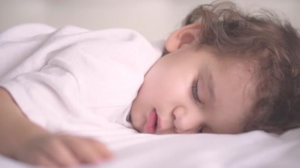 A kis aranyos fehér gyerek mosolyog álmában. Két éves kisbaba kényelmesen alszik.. — Stock videók