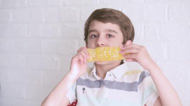 Küçük aç, şirin çocuk, tatlı mısırı zevkle yiyor. 6 yaşında tatlı bir çocuk evde haşlanmış mısır yiyor. Yüksek kaliteli FullHD görüntüler