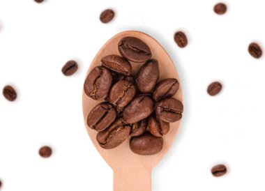 Beyaz arka planda izole edilmiş, ahşap kaşıkta taze kahve çekirdekleri.