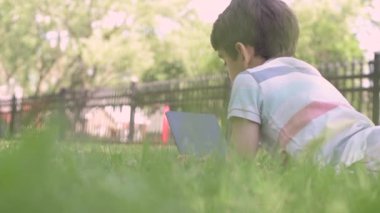Close up Child with a tablet PC sitting on the grass outdoors