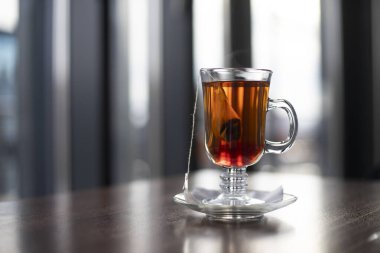 Cam bardaktaki poşette çay karışımı, bulanık bir arka planda. Yazı için yer