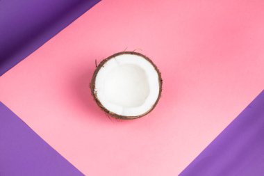 İzole edilmiş hindistan cevizi üst görünümü. Pembe ve mor arka planda yarım hindistan cevizi.