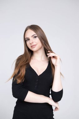 Uzun saçlı ve temiz tenli güzel bir kızın stüdyo portresi. Gri bir arka planda. Reklam için yer
