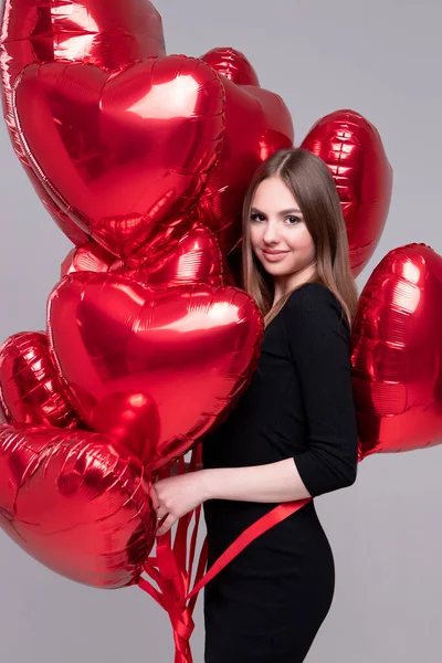 Sexy girl with a beautiful face. Model among red heart-shaped gel balloons.