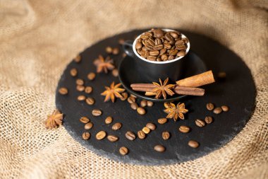 Morning drink. Cup of coffee with cinnamon and star anise on a background with sackcloth