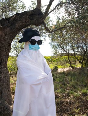 Bayram Cadılar Bayramı. Gözlüklü ve tıbbi maskeli bir hayalet.