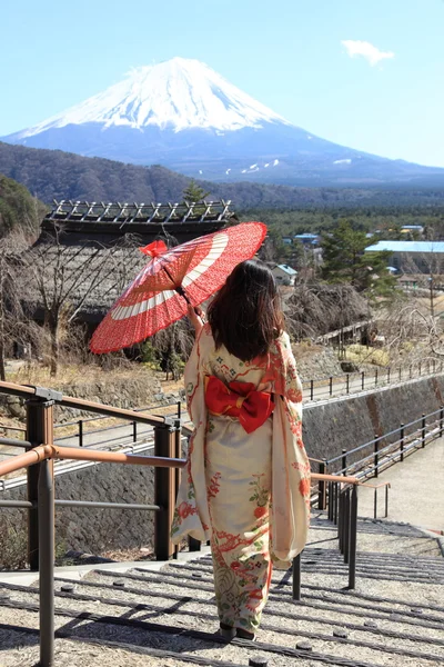 Japanse kimono vrouw met traditionele rode paraplu met fuji op de achtergrond — Stockfoto