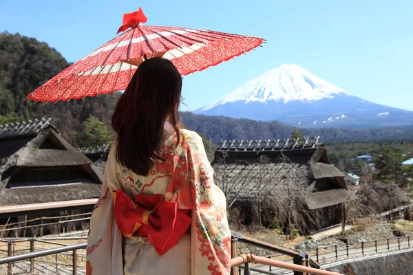 Giapponese kimono donna con tradizionale ombrello rosso con Fuji sullo sfondo Foto Stock