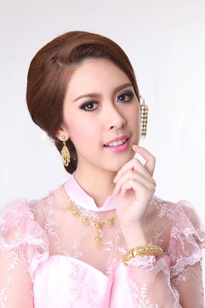 Elegante Mode brünette Frau posiert mit kreativer Chignon-Frisur und trägt rosa Thai-Kleid — Stockfoto