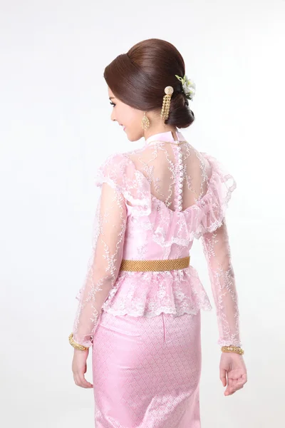 Elegant fashion brunette woman posing with creative chignon hair-style and wearing pink thai dress — Stock Photo, Image