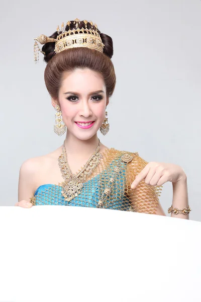 Elegant fashion asian woman posing with creative chignon hair-style and wearing blue thai dress standing behind a blank board — Stock Photo, Image