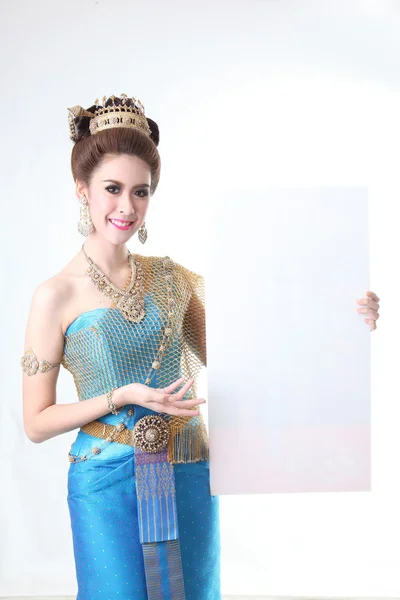 Elegante donna asiatica di moda in posa con chignon creativo in stile capelli e indossa abito thai blu in piedi dietro una tavola vuota Immagini Stock Royalty Free